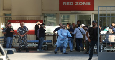 A group of people, including medical staff and other individuals, standing outside an emergency hospital entrance marked "Red Zone."