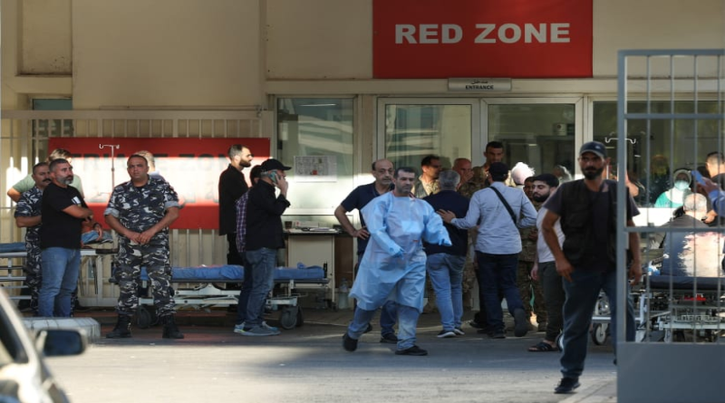 A group of people, including medical staff and other individuals, standing outside an emergency hospital entrance marked "Red Zone."