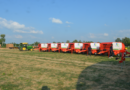 a row of farm equipment parked in a field