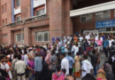 A large crowd gathers outside the entrance of a hospital building labeled "New O.P.D. Block" in India.