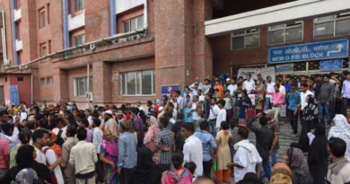 A large crowd gathers outside the entrance of a hospital building labeled "New O.P.D. Block" in India.