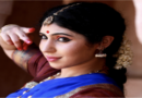 A woman dressed in traditional Indian attire poses gracefully for a photograph, showcasing vibrant colors and intricate designs.