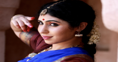 A woman dressed in traditional Indian attire poses gracefully for a photograph, showcasing vibrant colors and intricate designs.